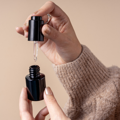 Hand holding a dropper bottle with dark Miron glass packaging, preserving the potency and freshness of skincare or essential oils.